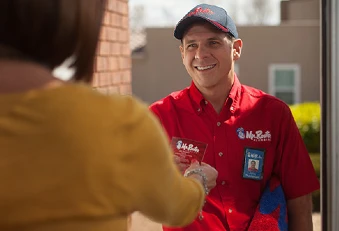 Smiling Mr. Rooter plumber arriving at home for job and being greeted by customer.