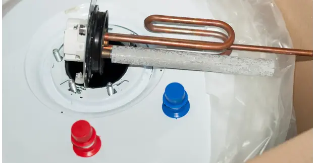 The top of a hot water tank undergoing water heater repair in Calgary, with blue and red cold and hot water connections and a new anode rod placed over the opening on top.
