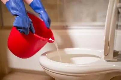 Hand pouring hot water into a toilet