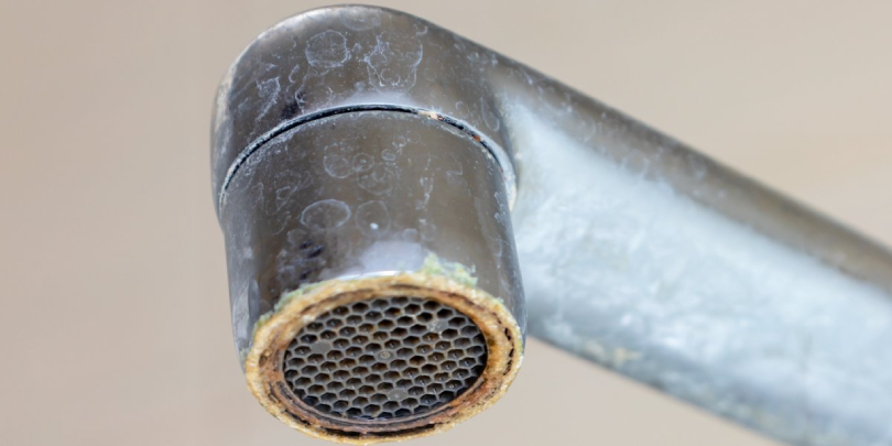 A faucet with built-up limescale and rust from hard water that could be reduced by installing a water softener in Calgary, AB.