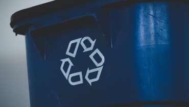 A close-up of the recycle sign on a blue recycling bin.