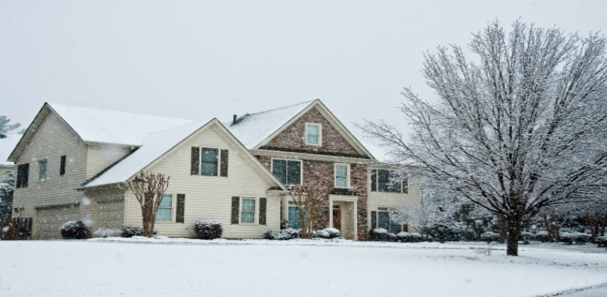 Residential home with stone front in a wintery day with snow on the lawn.