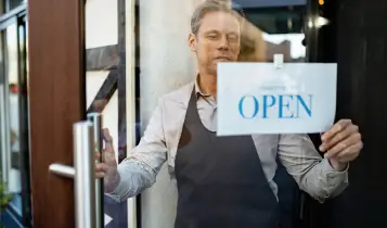 Man putting up an 'Open' Sign