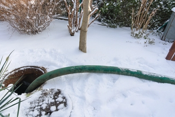 Residential septic tank being pumped out during the winter with snow on the ground.