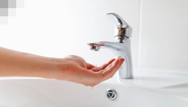 Person holding their hand under a faucet with low water pressure