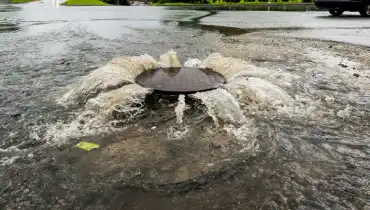 Street drain pipe overflowing with murky water