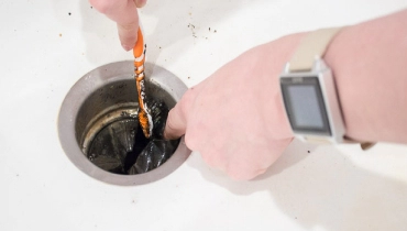 Hands cleaning a sink drain
