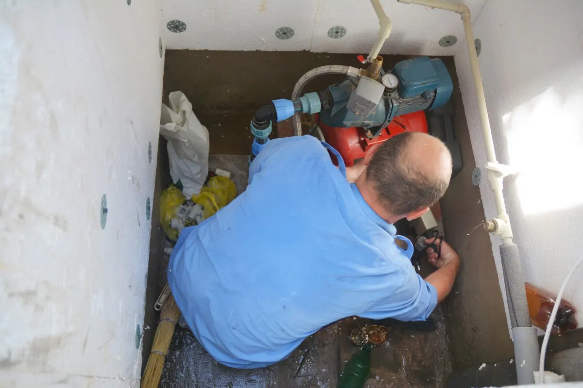 A plumber standing in a sump pit while completing sump pump repairs in Ottawa, ON.