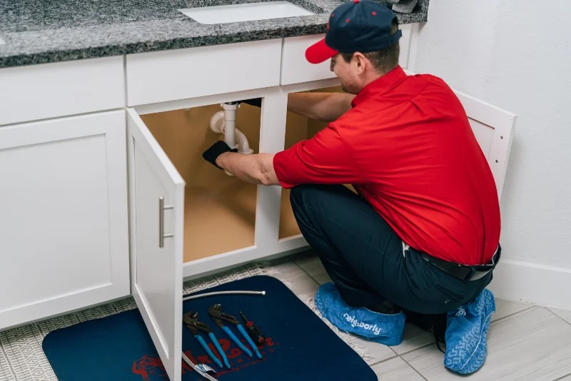 Service professional working on a clogged drain under a sink