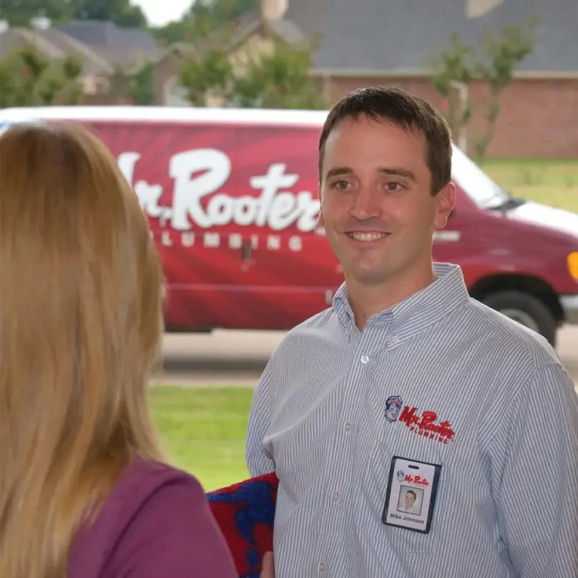 A plumber from Mr. Rooter Plumbing speaking with a homeowner at her door about her needs for drain cleaning in Nanaimo.