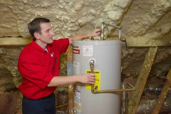 A plumber from Mr. Rooter Plumbing performing an inspection for a conventional hot water heater tank.