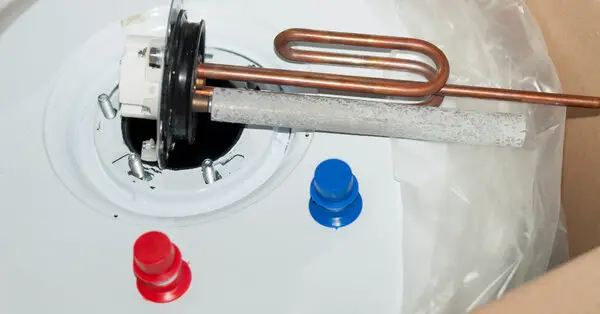 The top of a hot water tank undergoing water heater repair in Calgary, with blue and red cold and hot water connections and a new anode rod placed over the opening on top.