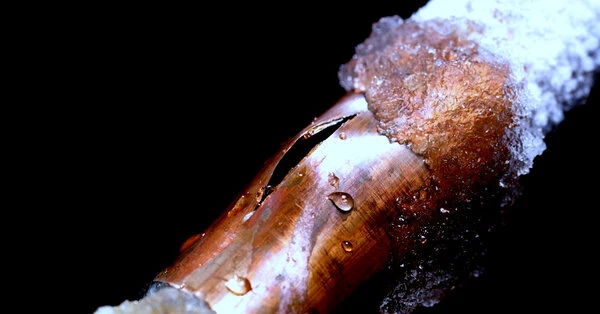 A pipe covered in ice with a crack in need of frozen pipe repair in Ottawa, ON.