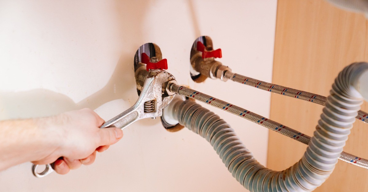 Mr. Rooter Plumbing technician using wrench to install a water heater in Markham home.
