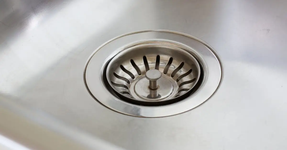 A stopper in the drain of a metal sink after a plumber has completed cleaning and repair services for a clogged drain in Scarborough, ON.
