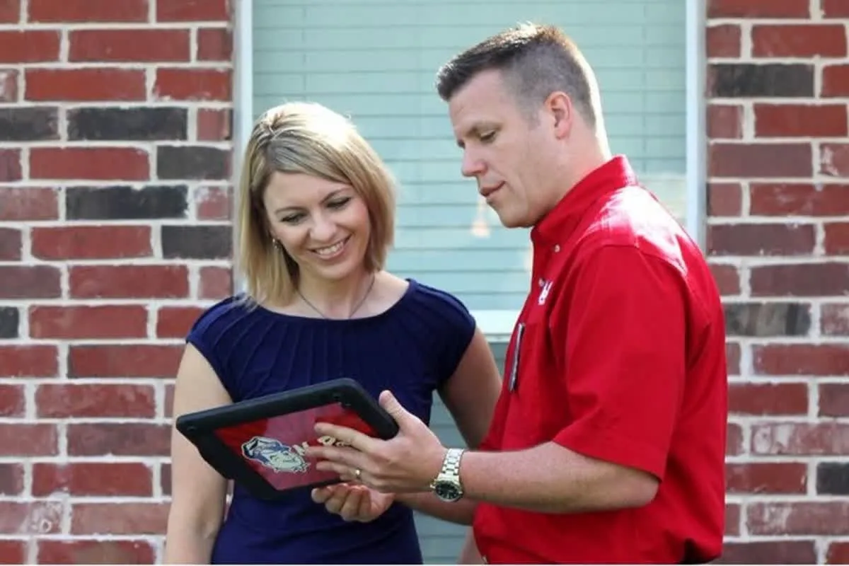 A plumber from Mr. Rooter Plumbing using a tablet to show a homeowner their options for trenchless sewer line repairs
