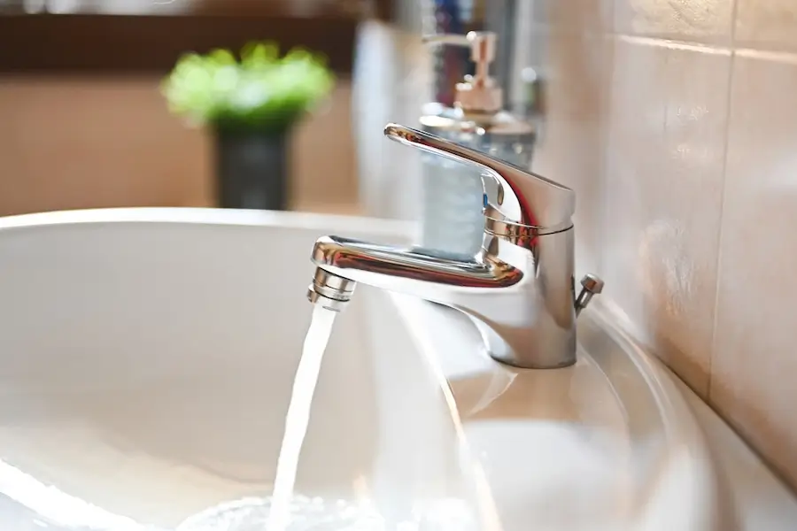 Clean water flowing from a bathroom faucet into the sink and down the drain.