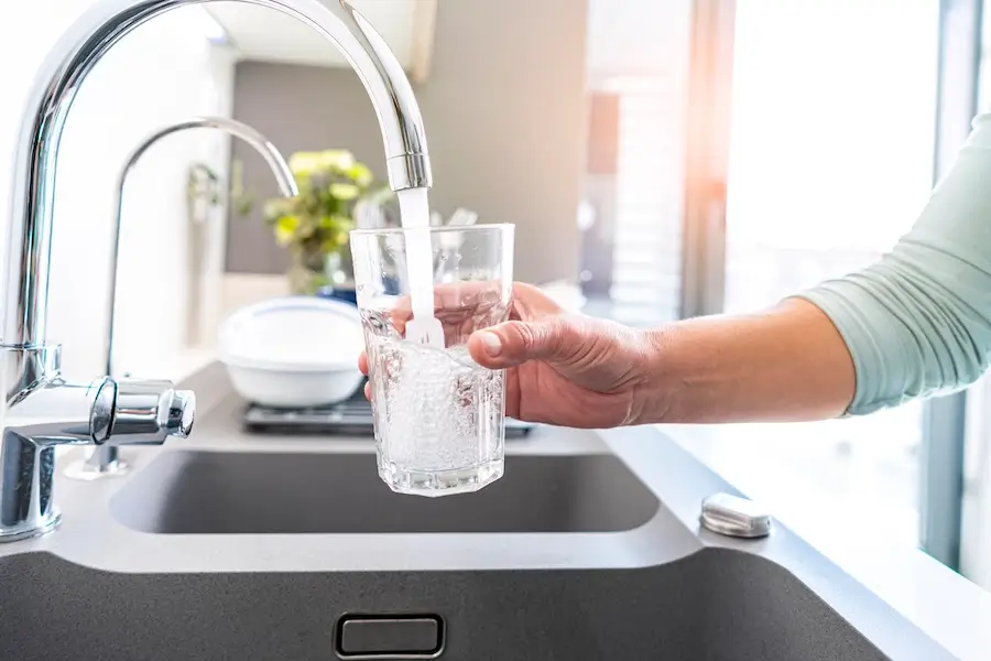 Close up of a woman filling a glass with clean tap water because of reverse osmosis technology. 