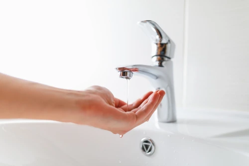 Hand under faucet with low-pressure water stream.