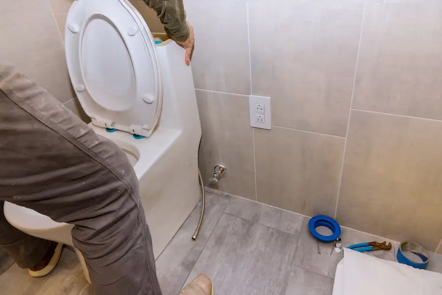 A plumber installs a new toilet in a home.