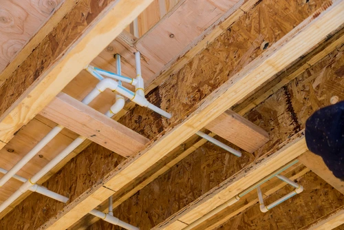 White PVC water pipes in a wooden home frame