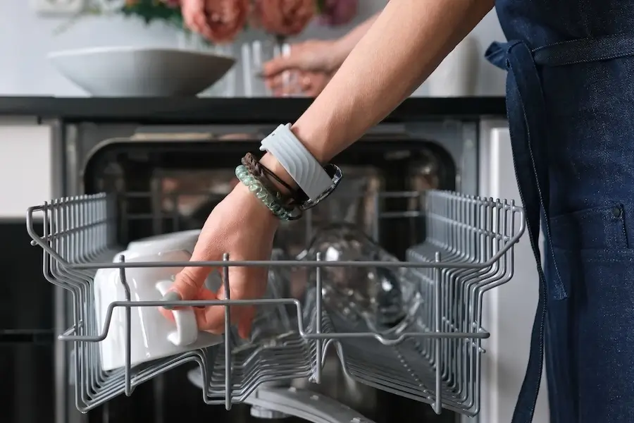 Woman unloading clean dishes from the dishwasher.