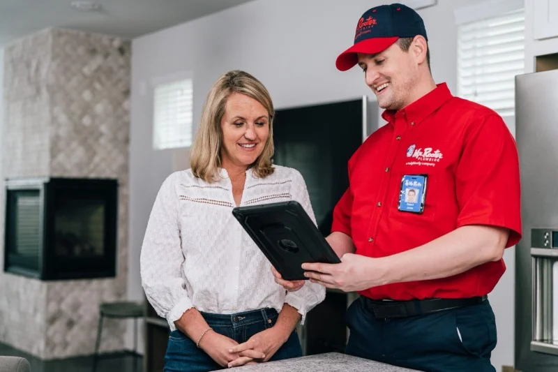 Mr. Rooter plumber discussing water softeners filters with woman