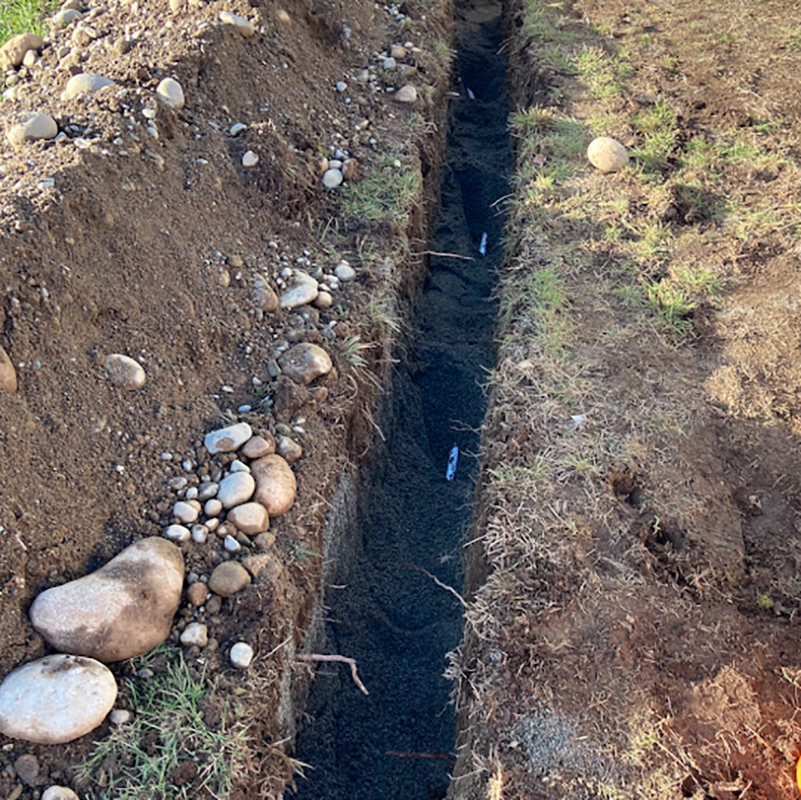 a trench has been dug to expose and replace a section of a water main line.